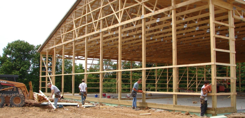 A group of men collaborates on the construction of a barn, showcasing teamwork and craftsmanship in the building process.